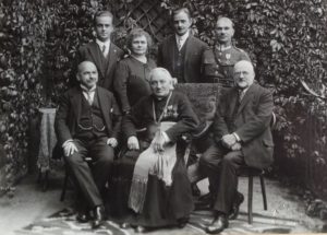 siedzą od lewej: Kuba Lewicki, biskup Bandurski, Wiktor Legeżyński senior, stoją od lewej: Wiktor, Maria z Michalskich, Michał Legeżyńscy, oficer
